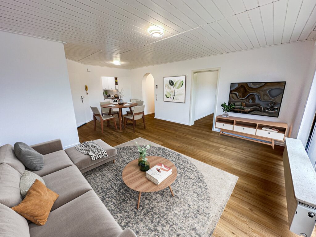 Modern eingerichtetes Wohnzimmer mit warmem Vinylboden in Holzoptik, gemütlicher Sitzecke und Essbereich im Hintergrund.